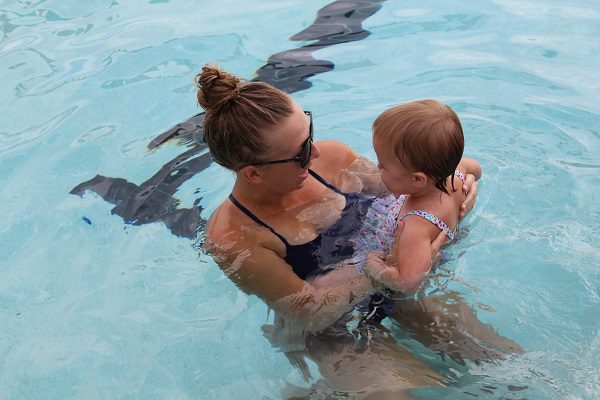 A swimming instructor holding a baby while in the pool