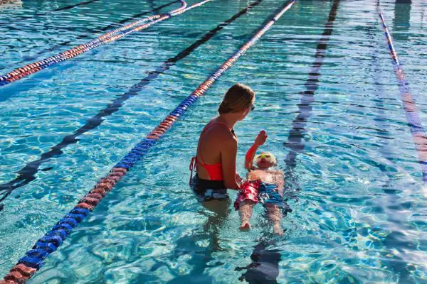 A swimming instructor teaching a boy how to float