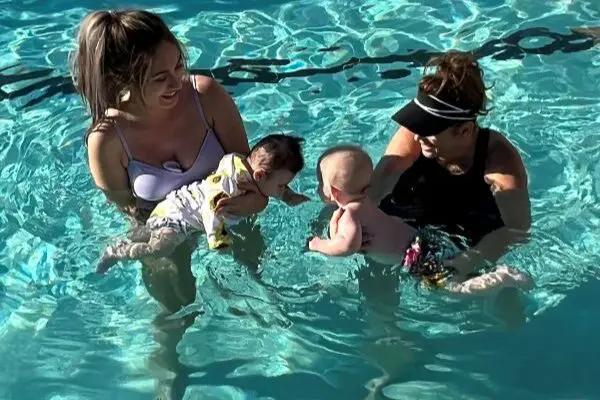 two mothers holding their babies while in the pool