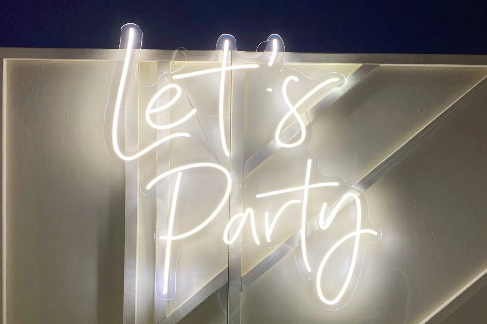 Lets Party Neon Sign on a Metallic Wall